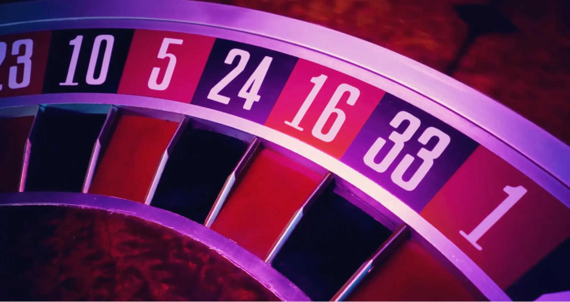 Ruleta — detail kola a čísel. Detail ruletového kola s čísly 23, 10, 5, 24, 16, 33 a 1 v neonovém osvětlení.